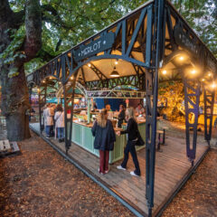 Open bartent, Koffietent, Wijnbar, open gevel met zwarte bogen, lichtgroene bar, houten vloer in een park met publiek